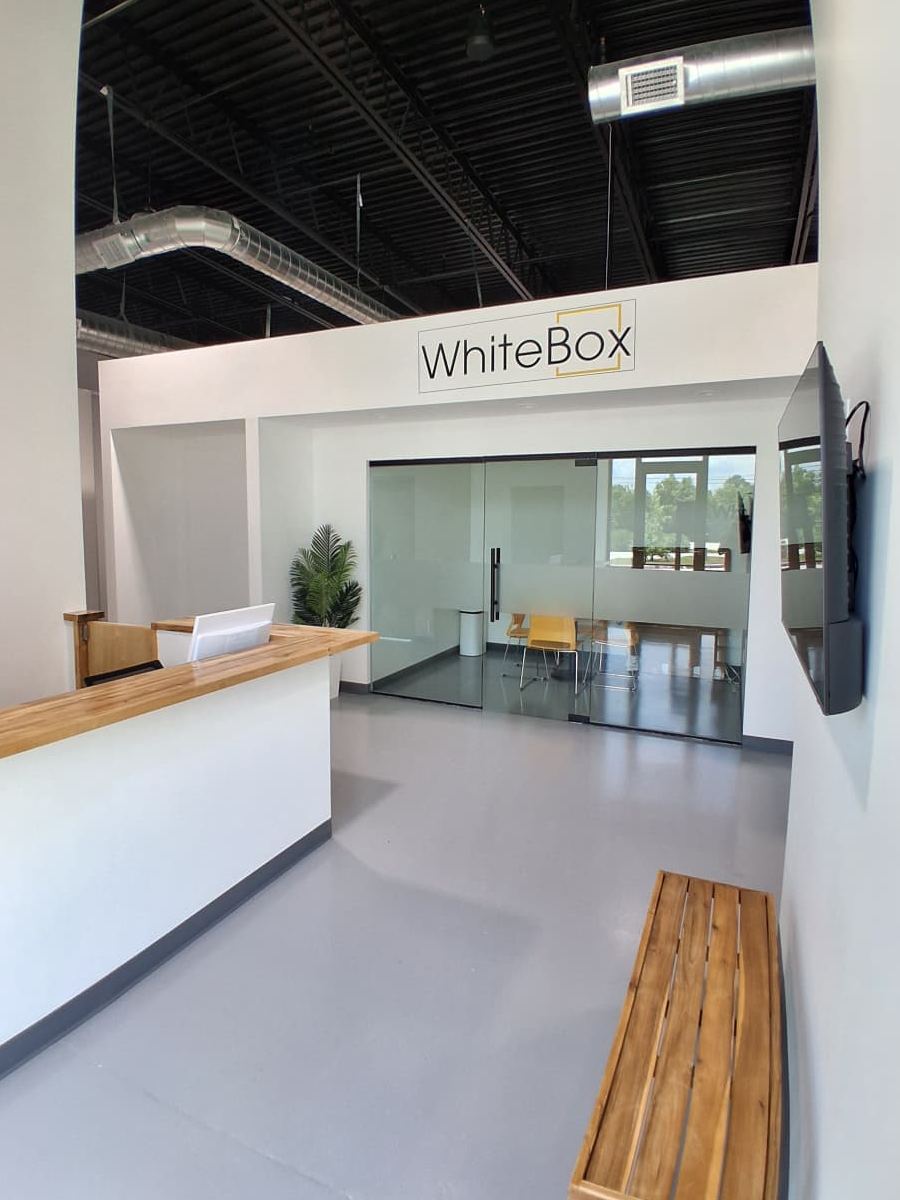 The WhiteBox lobby, with a wood-topped front desk and a glass-walled conference room