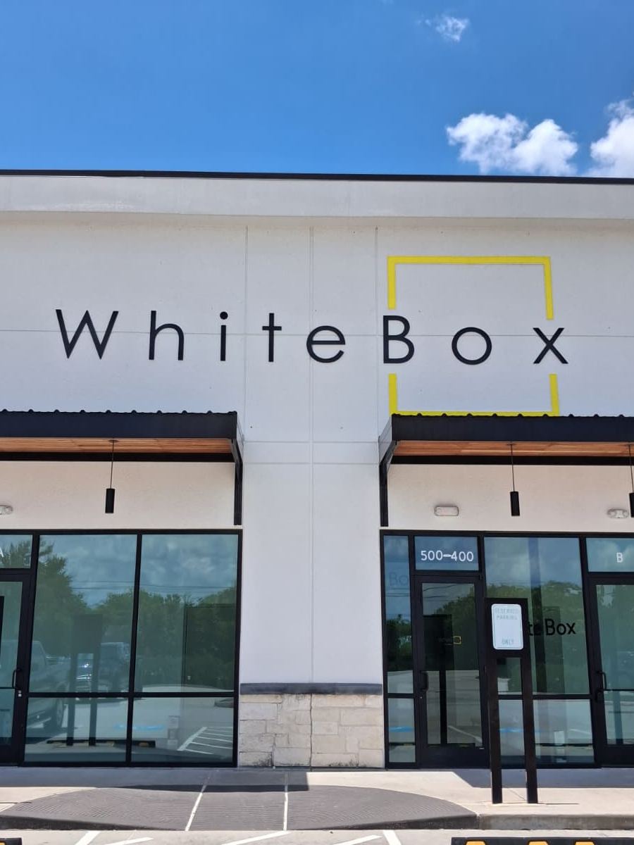 The WhiteBox storefront, with the black logo and yellow box mark above two glass entrances